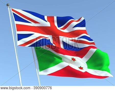 Two Waving State Flags Of United Kingdom And Burundi On The Blue Sky. High - Quality Business Backgr