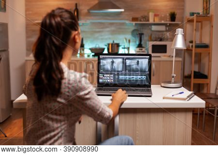 Back View Of Creative Filmmaker Working On A Movie On Laptop During Midnight. Content Creator In Hom