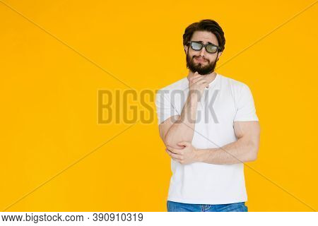 Young Bearded Man In A White T Shirt With 3d Glasses Watch A Movie Melodrama On A Yellow Background.