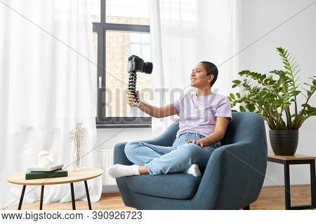 blogging, videoblog and people concept - happy smiling african american female video blogger with camera videoblogging at home
