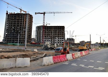 View On The Large Construction Site With Tower Cranes And Buildings On Sunset Background. Road Work 