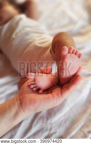Baby Feet In Mother Hands. Tiny Newborn Babys Feet On Female Shaped Hands Closeup. Mom And Her Child