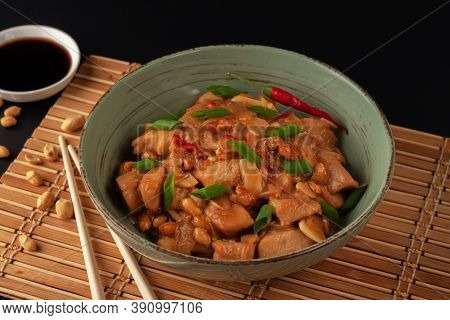 Kung Bao Chicken On A Black Background. A Chinese Dish With Chicken, Chili, Peanuts, Sauces And Onio