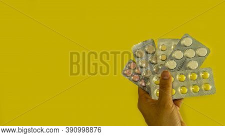 Pills In A Blister In Hand On A Yellow Background, Top View Space For Copying Banner Text Buy In A P