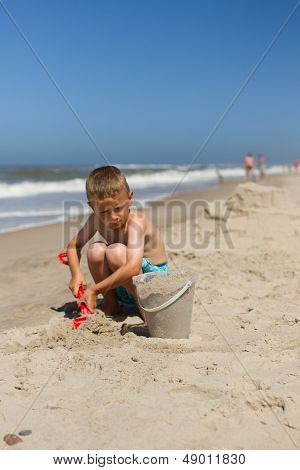 Boy Playing With Sand At The Beach