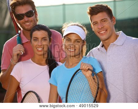 Retrato de sonrientes equipo joven del tenis en la cancha de tenis.