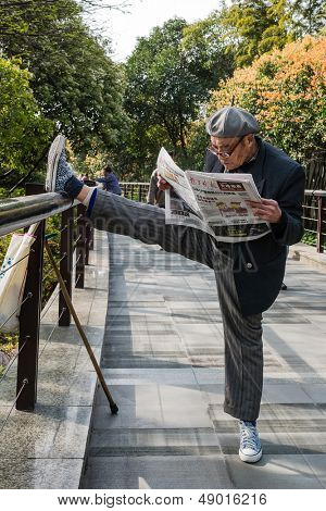 SHANGHAI - 7. APRIL: en gammel mand udøve strækker splits og læse avis i gucheng park  