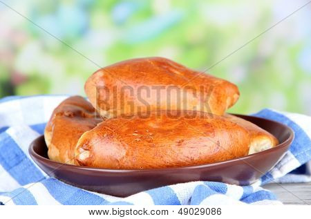 Empanadillas al horno frescos, en mesa de madera, sobre fondo brillante