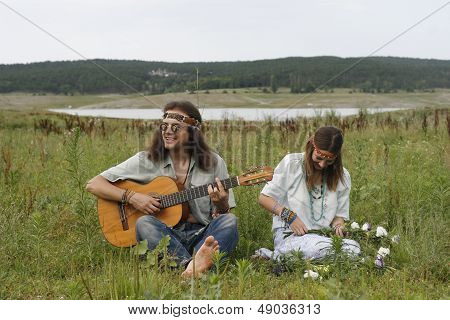 Hippie Men Play On The Guitar And Woman Make A Wreath