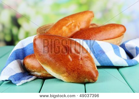 Empanadillas al horno frescos, en mesa de madera, sobre fondo brillante