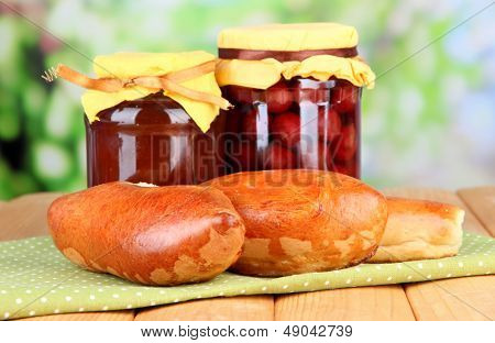 Empanadillas al horno frescos con mermelada de frutas, en la mesa de madera, sobre fondo brillante