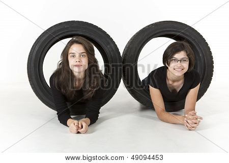 Two teenagers are playing with old tires