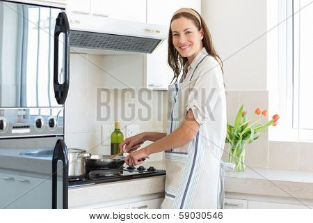 Portrait of a smiling young woman preparing food in the kitchen at home