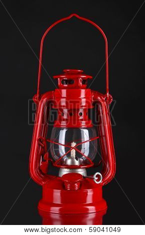 Red kerosene lamp on black background