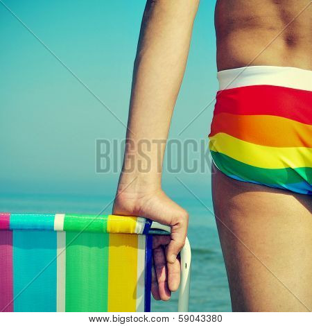 someone wearing a rainbow swimsuit and a colorful deck chair on the beach