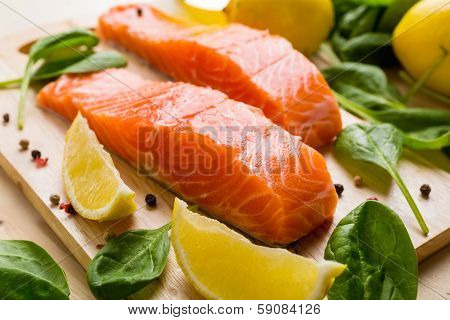 Fresh Salmon Steaks with Lemons and Baby  Spinach  on a Cutting Board