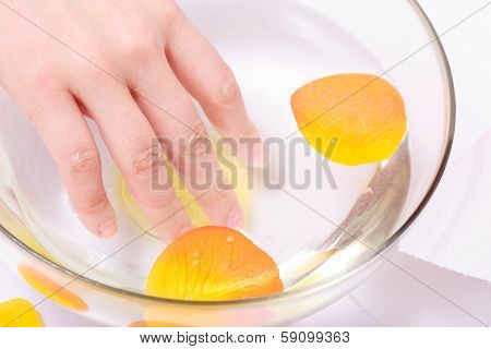 Female Hand Soaking In Glass Bowl Of Water. Manicure Spa Beauty Salon.