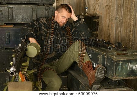 Thoughtful armed soldier sits
