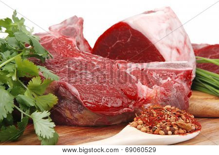 raw meat : fresh beef pork big rib and fillet with garlic and green stuff on wood isolated over white background