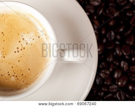 Top View Of A Cup Of Dark Roasted Coffee With Coffeebeans In The Background