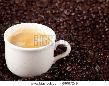 Fresh Cup Of Dark Roasted Coffee With Coffeebeans In The Background