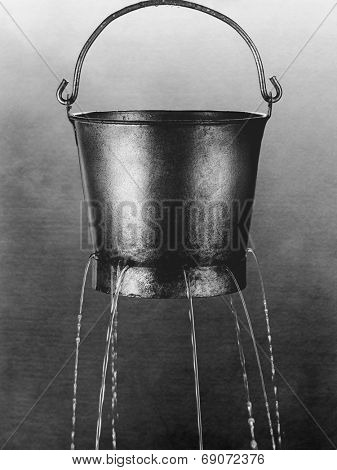 Water poring through holes in bucket (b&w)