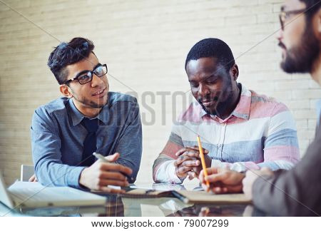 Three male employees discussing working plans at meeting