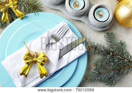 Christmas table setting in blue, golden and whitec olors on grey tablecloth background