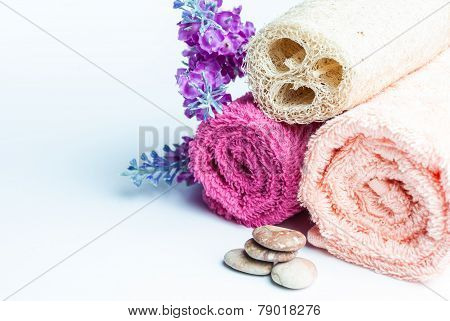 Spa towels rolls flower and stones lying on shite background. Space for your text. Horizontal composition.
