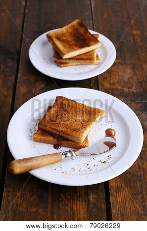 Toast bread with chocolate on plate with knife on wooden table background