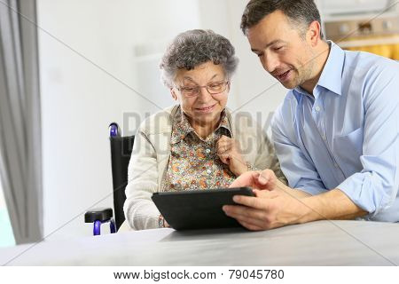 Man with elderly woman using digital tablet