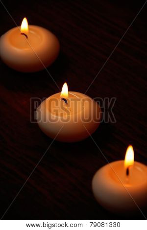 Three Candles On A Dark Wooden Table.
