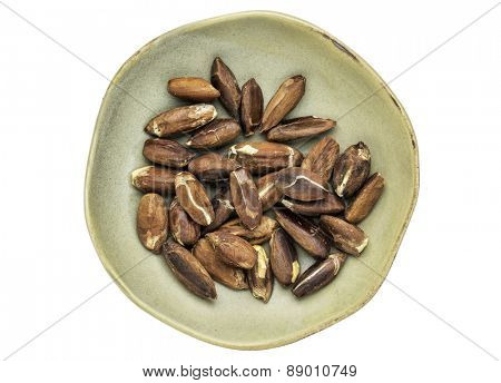 roasted pili nuts grown in Philippines, top view of ceramic bowl isolated on white
