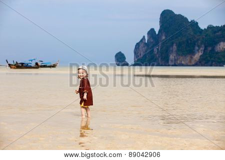 Child Walking On Fine Sand Through The Water