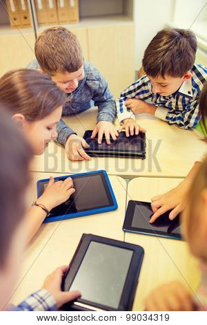 education, elementary school, learning, technology and people concept - group of school kids with tablet pc computer having fun on break in classroom