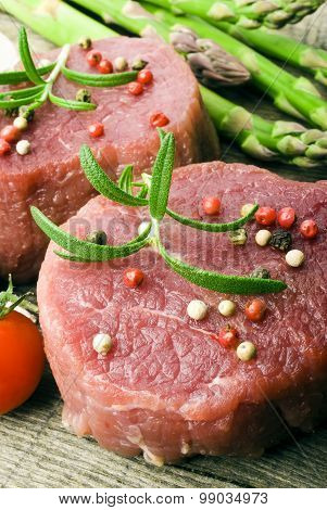 Raw Steak with green asparagus on wooden board