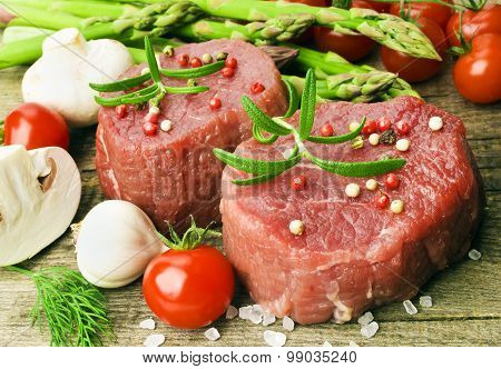 Raw Steak with green asparagus on wooden board