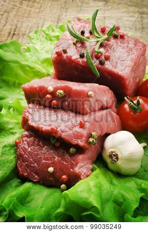 Raw Steak with green lettuce on wooden board