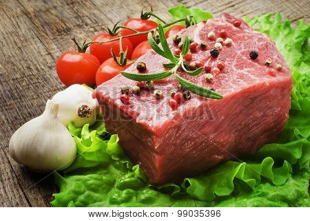 Raw Steak with green lettuce on wooden board