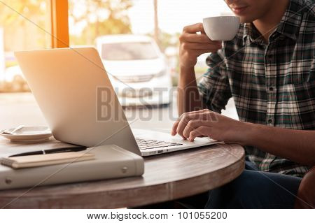 Businessman Using Laptop With Tablet And Pen On Wooden Table In Coffee Shop With A Cup Of Coffee