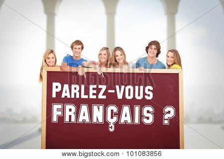 Smiling group of people with a blank space as they point to it against bright room with columns