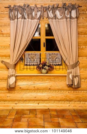 Wooden lodge made of logs, elements of interior, window with curtains