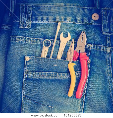 Several tools on a denim workers pocket.