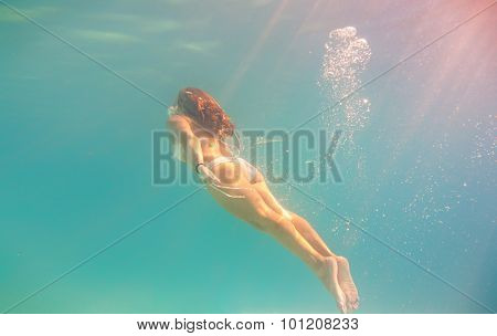 Young woman swimming undewater in the swimming pool