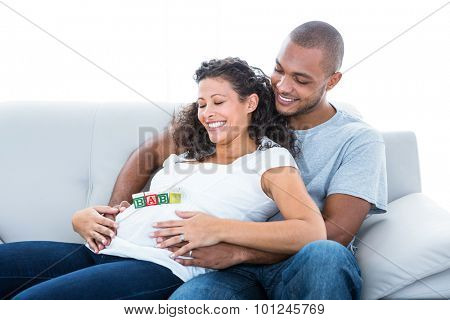 Cheerful couple enjoying sitting on sofa with toy at home