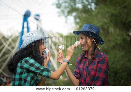 two beautiful girls in cowboy hats eating ice cream