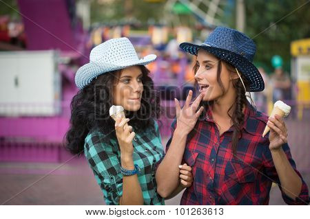 two beautiful girls in cowboy hats eating ice cream