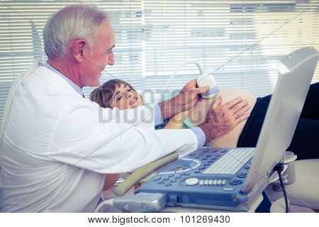 Male doctor doing ultrasound test on pregnant woman in hospital