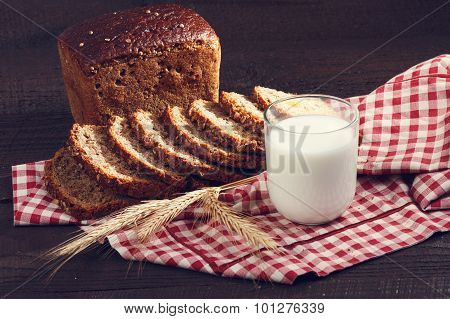 Wholegrain Bread And Milk With Spikelets Of Wheat On A Cloth On A Dark Boards