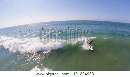 LOS ANGELES - NOV 23, 2014: Woman rides on surfboard at autumn sunny day. Aerial view. The art of surfing was first described in 1769.
